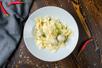 Farfalle with chicken meatballs and creamy sauce on wooden table top view