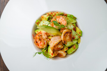 salad with shrimp and avocado on white plate on wooden table