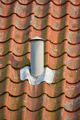 Ventilation pillar and chimney on rooftop of a house or factory building contributing to air pollution. Construction of an exterior chute for air flow with copyspace for cooling and heating control