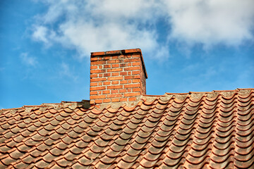 Red brick chimney designed on the roof of residential house or building outside against a cloudy...
