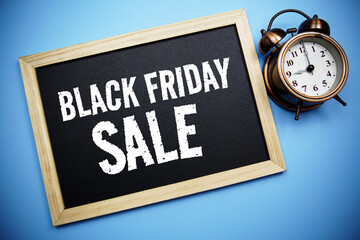 Black Friday Sale text message on Blackboard and alarm clock on blue background