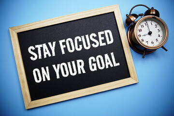 Stay Focused on your goal word with alarm clock on blue background