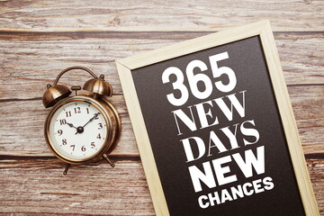 365 New Days New Chances word with alarm clock on wooden background