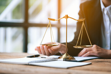 Close up of lawyer's hands and scale of justice on table in the office.