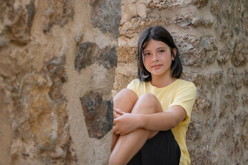 A young girl sits on a stone wall.