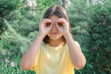 A young girl makes glasses with her hands.