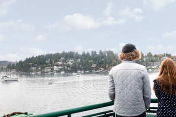 Fototapeta premium A view of a young couple standing at the railing of a ferry boat, looking out onto Friday Harbor Marina.