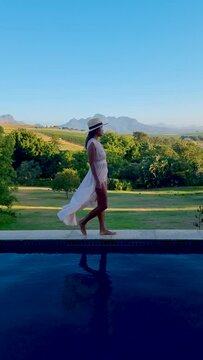 women in the swimming pool looking out over the Vineyards and mountains of Stellenbosch South Africa. 