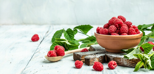 Red raspberries in bowl on white wooden background. Organic Raspberry. Red berry. Long banner format. place for text