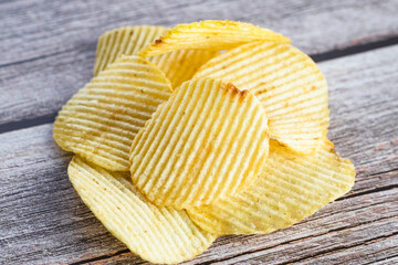 Crispy potato chips on the wood table background. Home made potato chips served with mustard, rosemary, fleur de sel salt on wood background.  Copy space.
