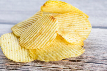 Crispy potato chips on the wood table background. Home made potato chips served with mustard, rosemary, fleur de sel salt on wood background.  Copy space.