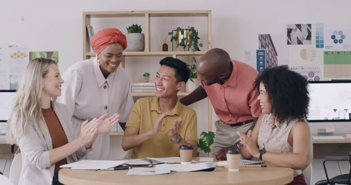 Designers clapping hands and cheering during a productive meeting. Cheerful diverse colleagues celebrating their success after achieving project financial goals at a startup company