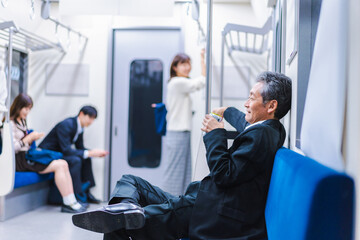 電車内で飲酒をする中年の男性