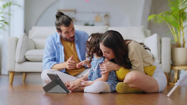 Happiness Family sitting in casual living room with wireless Internet connection at home, Girl daughter watching video on tablet, parents is cheering up her online study together with laugh smile fun