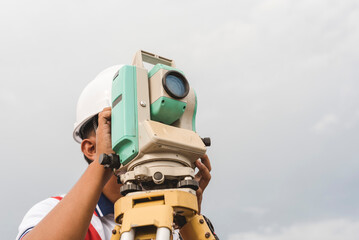 A land surveyor operating a Total Station or RTS. Surveying equipment at the field.