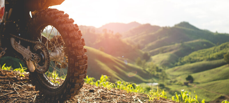 Part of a motocross wheel on a mound, with sunrise.beautiful mountain scenery backdrop adventure concept. copyspace for your individual text
