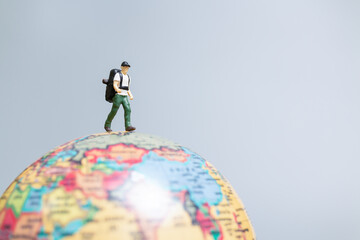 Travelers in miniature standing on the globe and making their way to their destination, Travel...