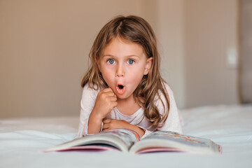Fantasy literature. Emotional child girl read interesting book in bed. Small kid enjoy reading. Developing child fantasy and imagination. Imaginary world. Fairy tale. Bedtime reading