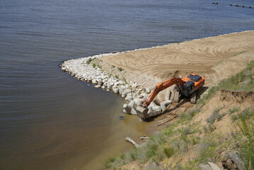 Fototapeta premium The excavator levels the sandy bank of the Volga River. Ulyanovsk. Russia