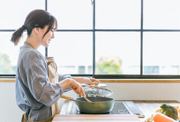キッチンでフライパンを使う女性  © buritora