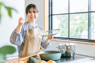 キッチンで料理の味見をする女性
