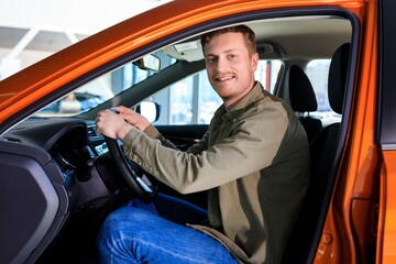 A smiling man is driving a new car. Happy buyer at the dealership