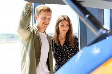 A young couple is standing near a new machine in a dealership. The first expensive family purchase