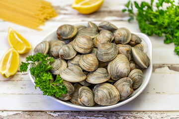 Fresh Littleneck Clams on a white plate with parsley.