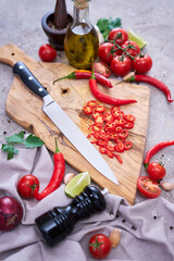 Fresh red chili peppers round slices on wooden cutting board at domestic kitchen