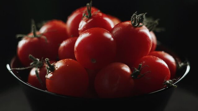 Cherry tomatoes on a black background in water drops