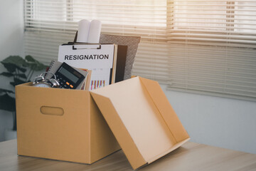 Concept of termination of employment and resignation. Quitting a job, The big quit. Resignation.Letter of resignation and cardboard box on the desk.