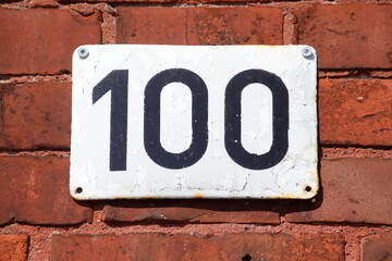 Hausnummernschild Nummer Einhunert, Backsteinmauer, Deutschland