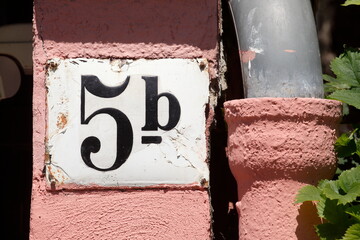 Weisses Hausnummernschild Nr. 5b auf rosa Hauswand, Abflussruhr, Deutschland