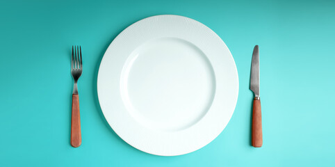 White Empty Plate with Fork and Knife Lay on Blue Table Background. Food Shortage, World Food Crisis Issue. Table Top View