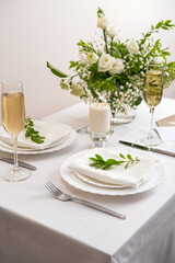 Wedding teble decoration with white flowers, glasses and white napkins. Elegantly decorated table at a wedding reception. Festive table setting. The wedding decor.