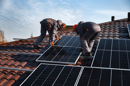 workers installing solar panels on the roof