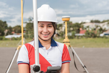 An asian female land surveyor operating a GNSS receiver. Using RTK geodetic surveying equipment.