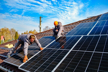 Solar panel technician installing solar panels on roof. technician in blue suit installing photovoltaic blue solar modules. Electrician panel sun sustainable resources - obrazy, fototapety, plakaty