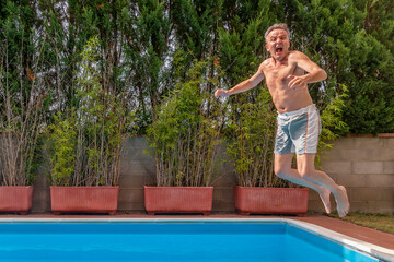 A middle-aged white man dives into the pool making a very funny expression
