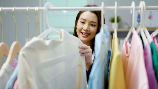 Beautiful woman business owner at fashion store choose clothes in the clothes rail, Fashion designer standing in order to repair, service for customers. Concept Profession Dressmaker designer