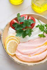 Close-up of beige and pink greek tarama dip with tomatoes, fresh parsley and lemon, vertical shot on a beige stone background