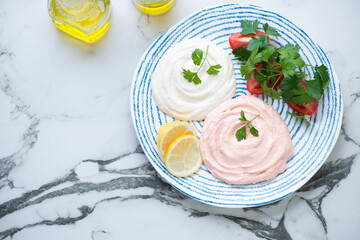 Blue and white plate with two types of taramasalata or greek fish roe dip, top view on a black and white marble background, horizontal shot with space