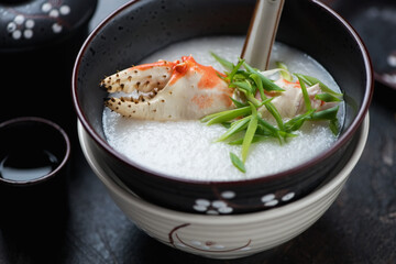 Closeup of crab congee or a type of asian rice porridge, studio shot on a dark-brown stone background