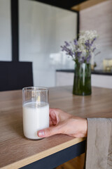 A glass of milk drink or yogurt in the hands of a girl. The concept of lactose intolerance. Transparent glass with tasty milk