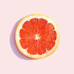 Red sliced grapefruit on a pastel pink background. Minimal summer fruit composition.