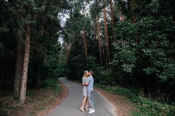 A guy and a girl are standing in the forest, hugging and kissing