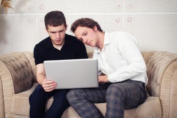 Gay couple at home. Two guys are sitting on the couch.	