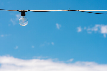 Vintage light bulb with blue sky and white clouds on background. Electricity concept. Earth hour....