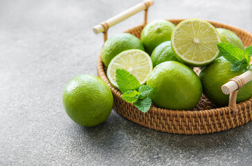 Green  Limes with fresh mint leaves on wicker tray
