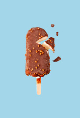 one white popsicle in chocolate glaze with nuts on a blue background, selective focus